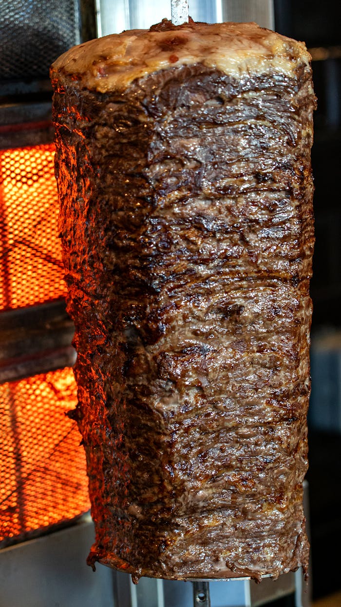Close-up of seasoned beef shawarma cooking on a vertical rotisserie. Perfect for Mediterranean cuisine lovers.
