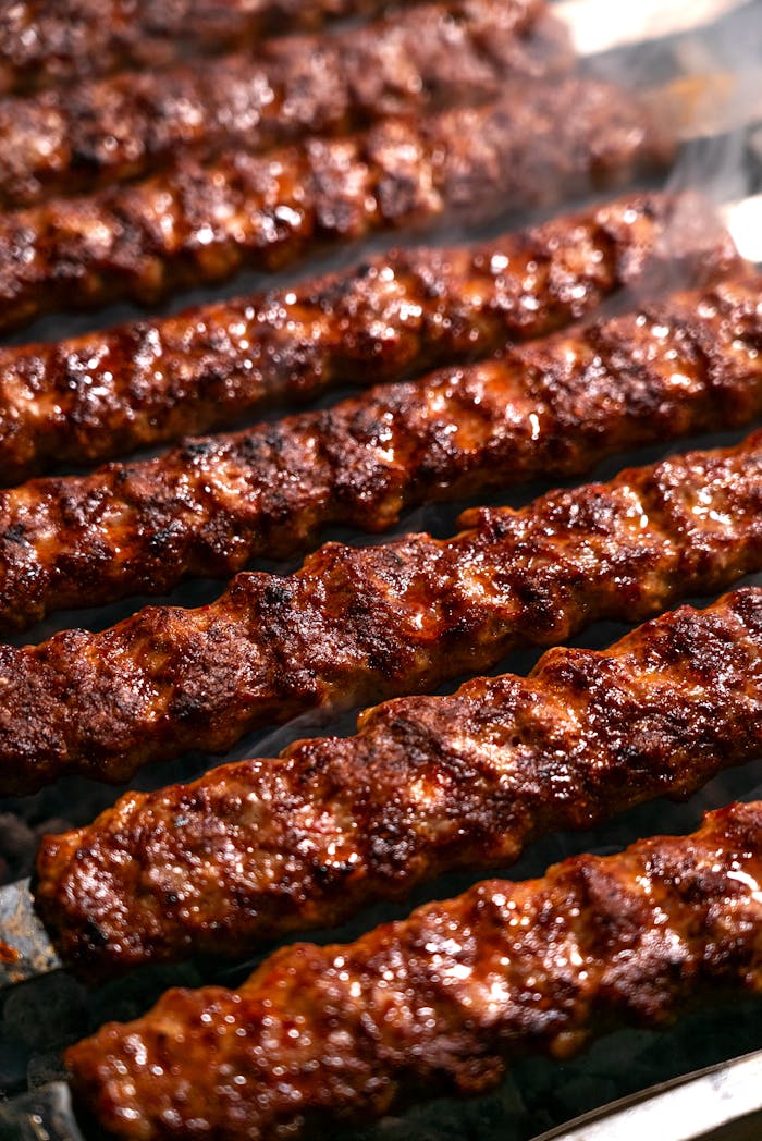 Close-up of sizzling meat kebabs on a grill with smoke rising, perfect for barbecue enthusiasts.